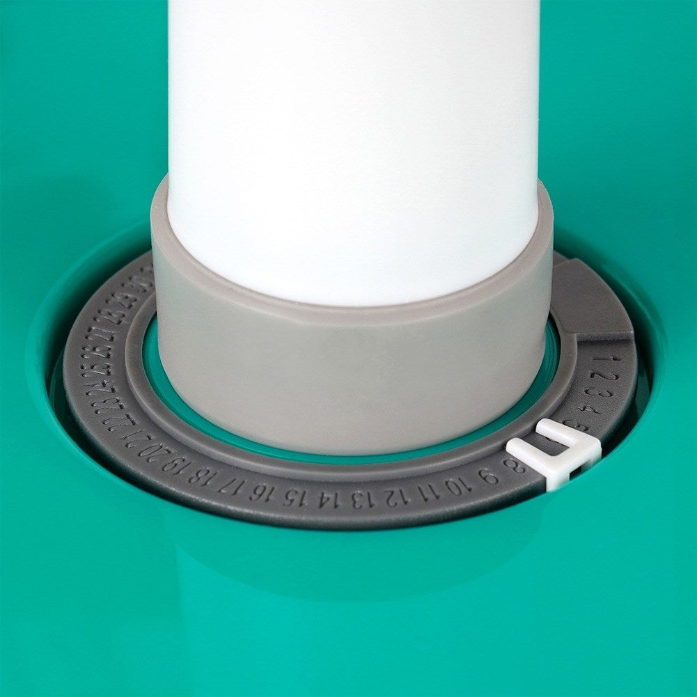 Primer plano de un tubo blanco sobre una superficie verde con un anillo de ajuste numerado.
