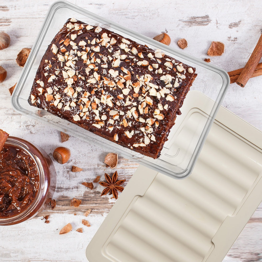 Pastel de chocolate con nueces en recipiente, junto a frasco de crema y canela.