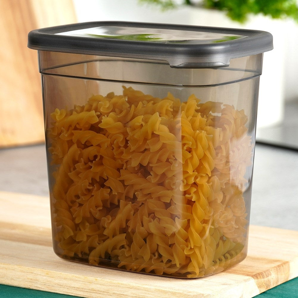 Un recipiente transparente lleno de pasta fusilli amarilla bajo una tapa oscura.