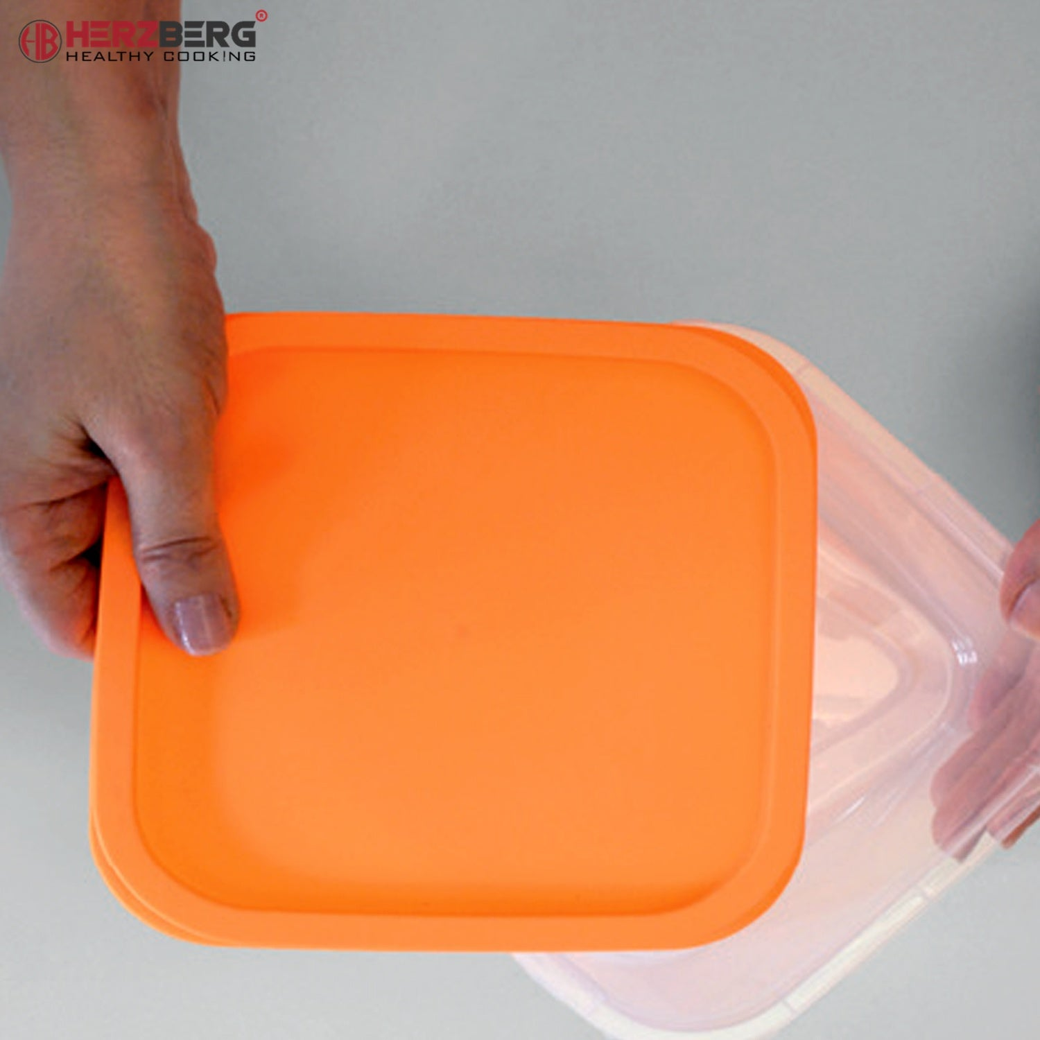 Una mano sostiene una tapa naranja brillante sobre un recipiente transparente.