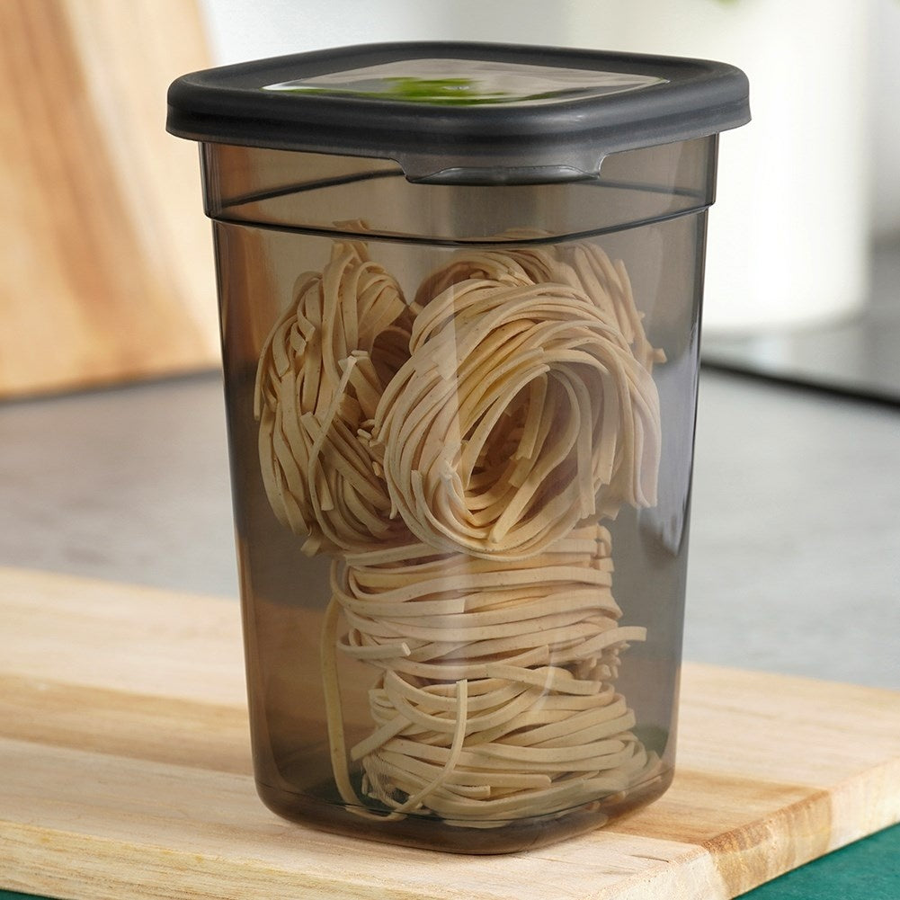 Un recipiente transparente con tapa negra, lleno de pasta.
