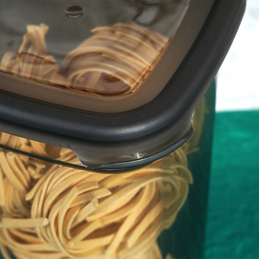 Primer plano de pasta fettuccine seca en un recipiente de vidrio con tapa negra.