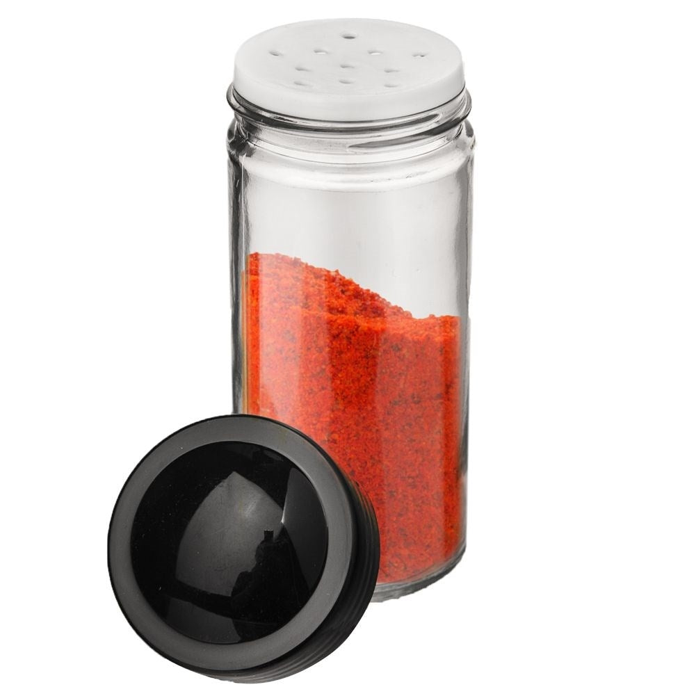 Frasco de especias de vidrio con polvo rojo y tapa negra abierta al lado.