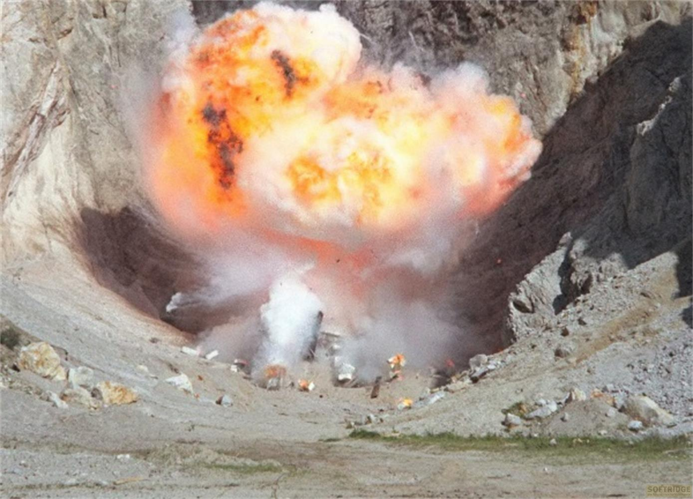 Un'esplosione in un cratere con fuoco arancione e molto fumo.