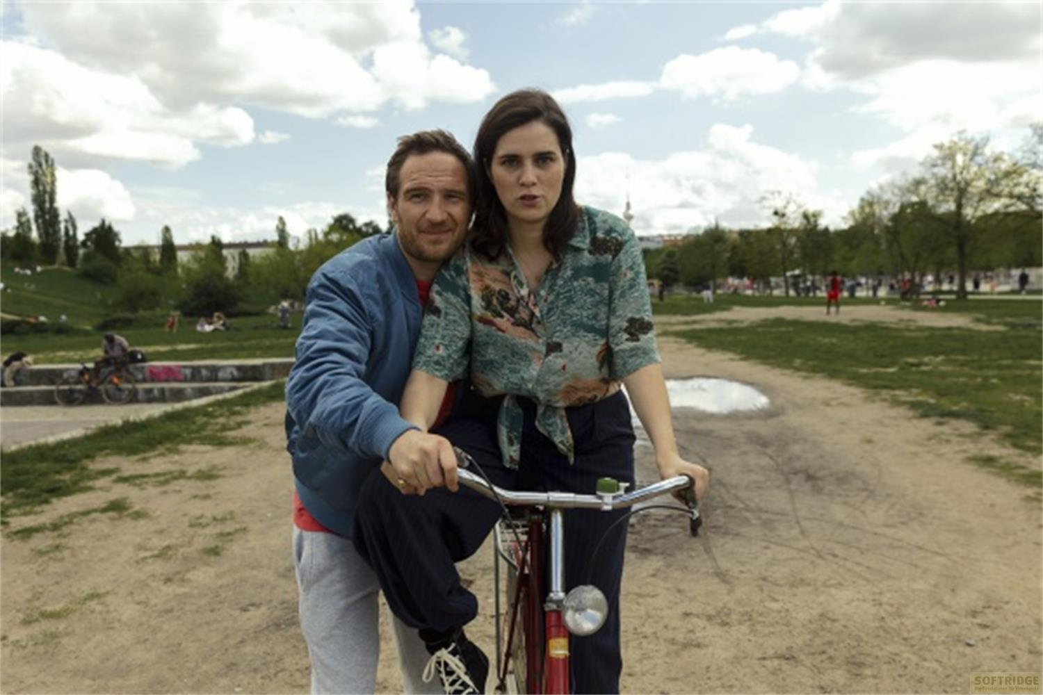 Un uomo e una donna su una bicicletta in un parco in una giornata nuvolosa.
