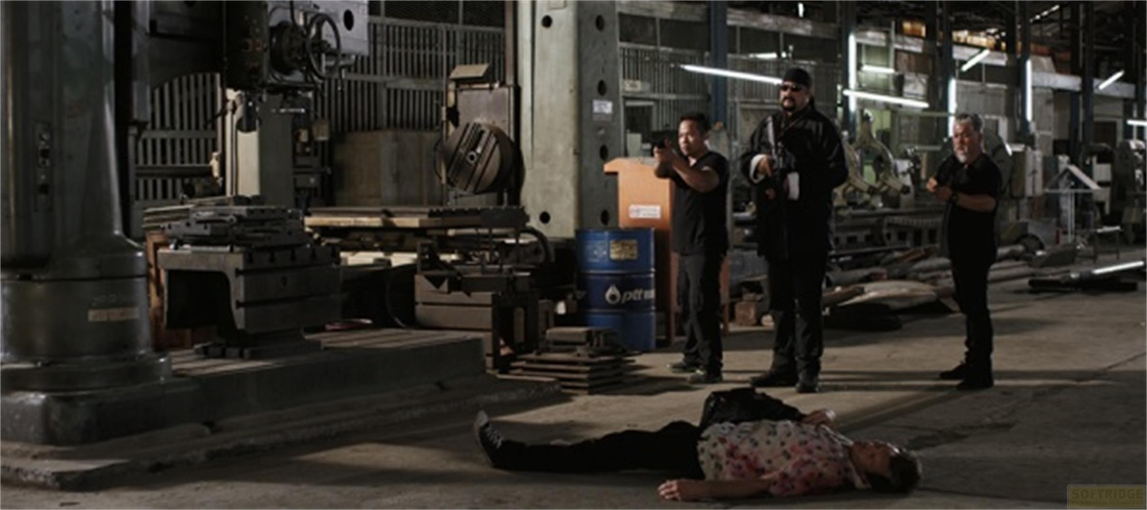 Trois hommes dans une usine, l'un au sol. Un homme tient une arme.
