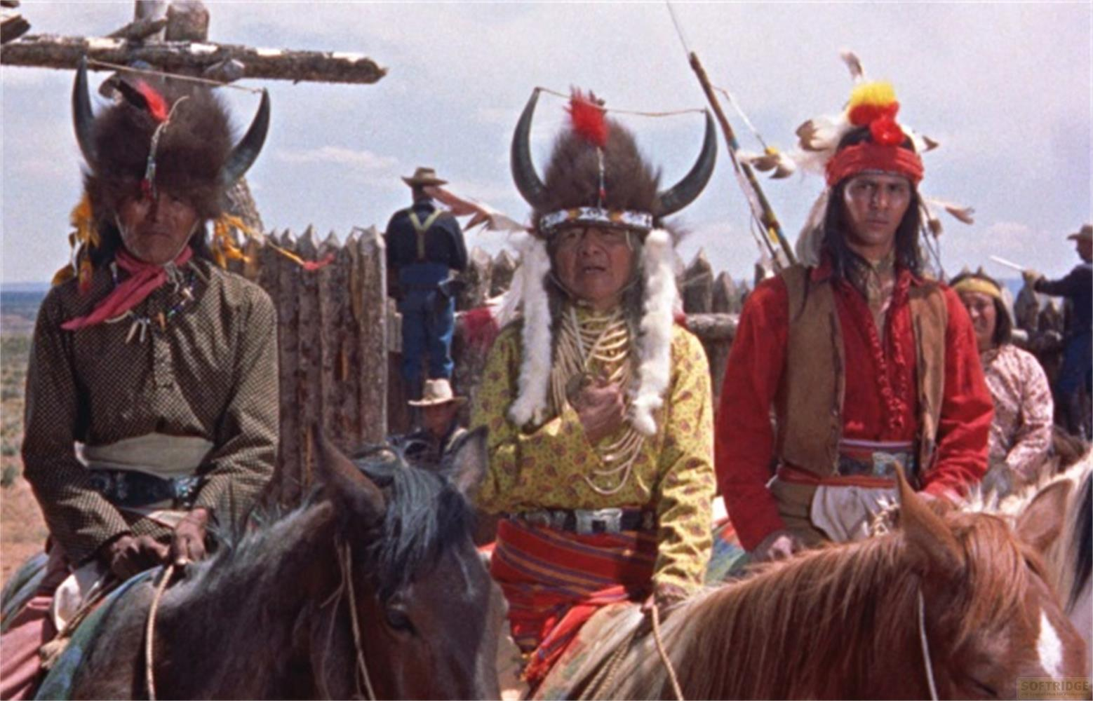 Tre uomini indigeni a cavallo, adornati con copricapi e abiti tradizionali.