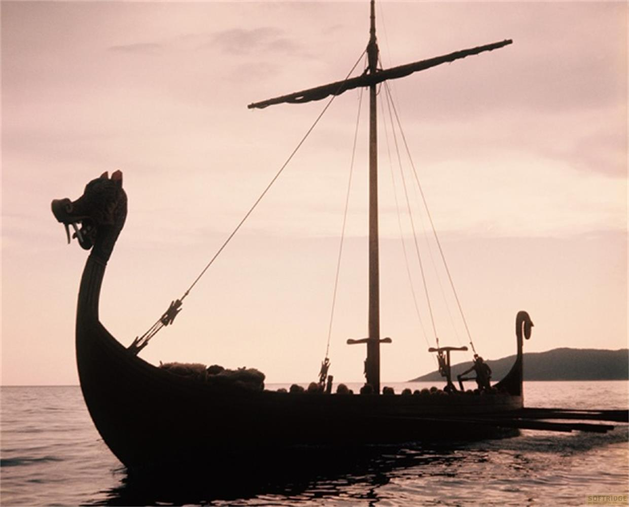 Una nave vichinga con prua a testa di drago e vela al tramonto.