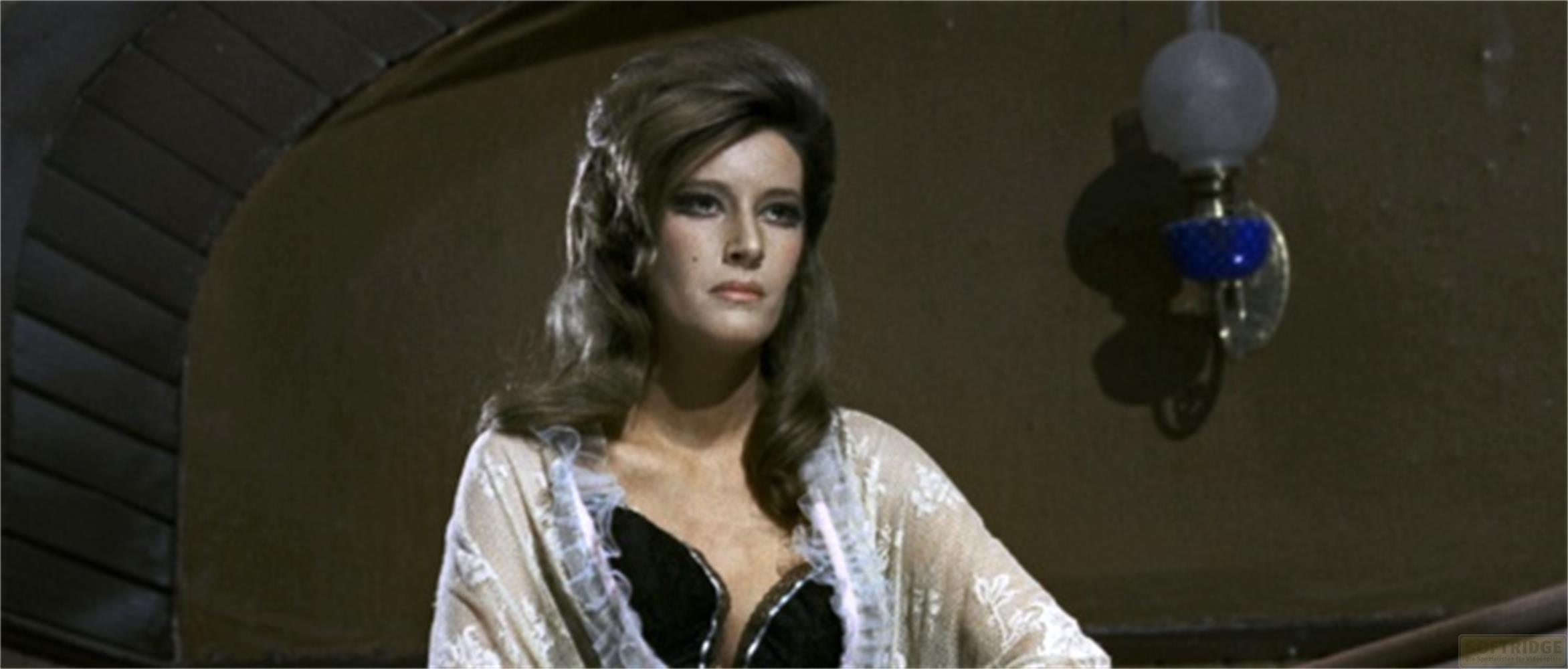 Una donna dai capelli voluminosi indossa un top nero e un coprispalle di pizzo bianco.