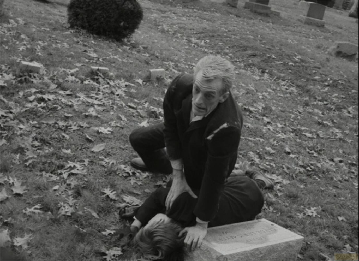 Uomo inginocchiato su bambino su lapide in cimitero.