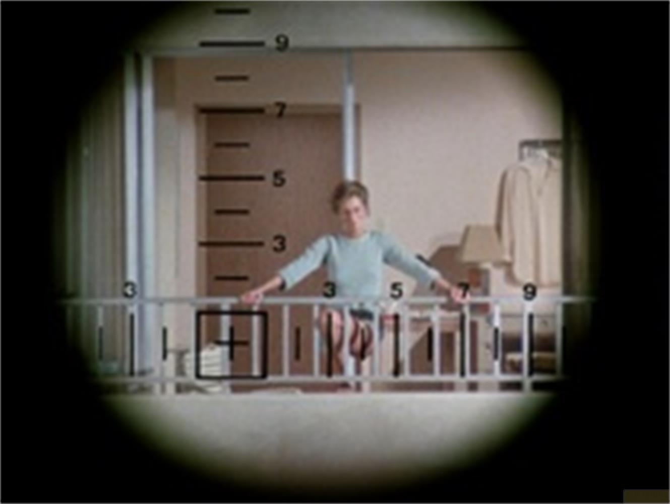 Vista attraverso un reticolo di una donna su un balcone con una scala.