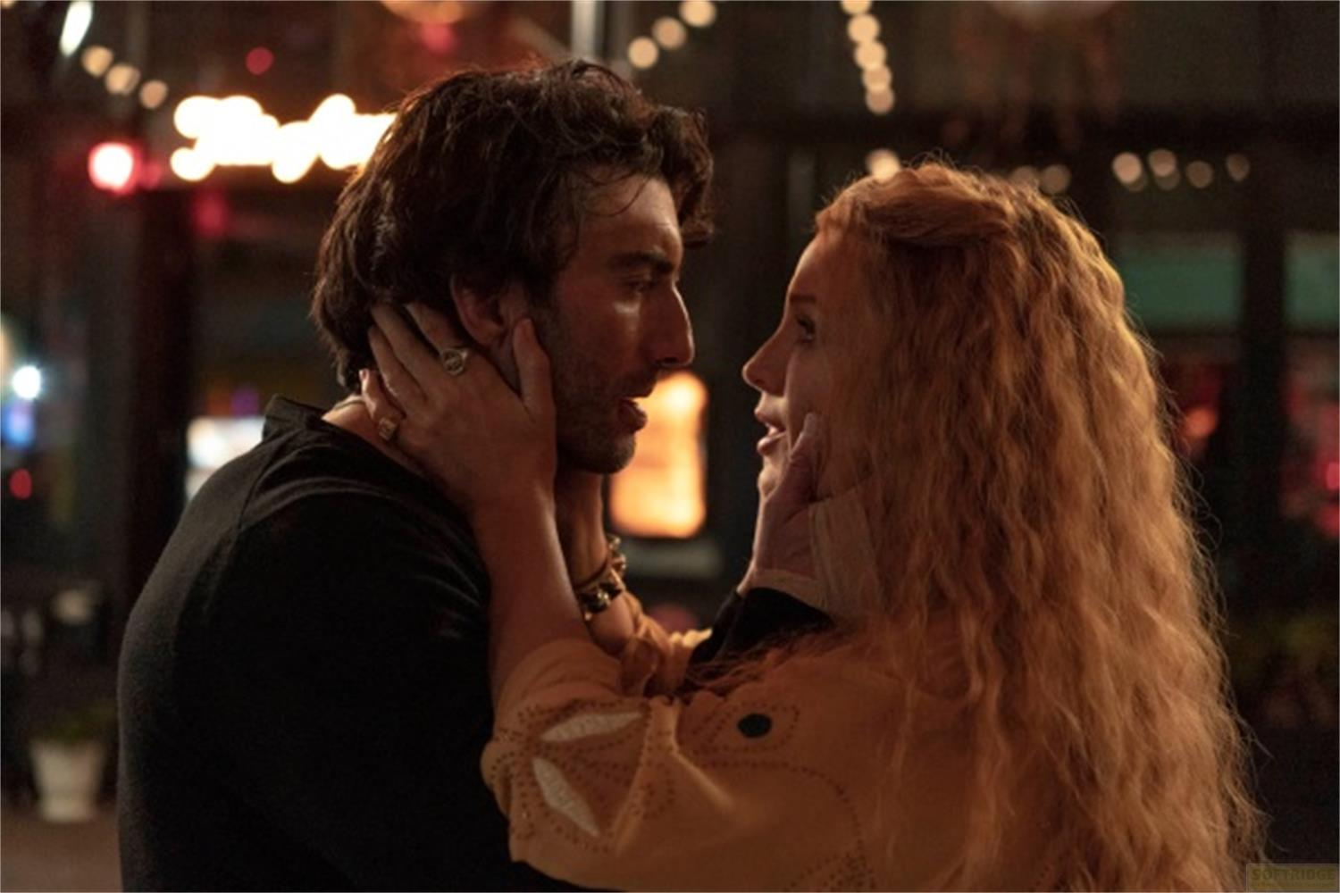 Un uomo e una donna si abbracciano all'aperto di notte. Luci sullo sfondo.