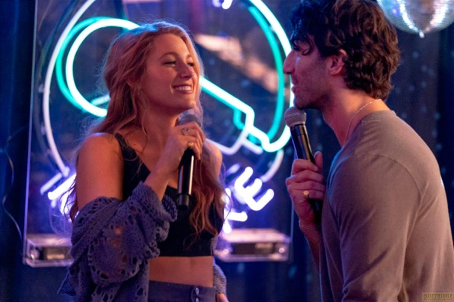 Un uomo e una donna cantano nei microfoni con luci al neon.