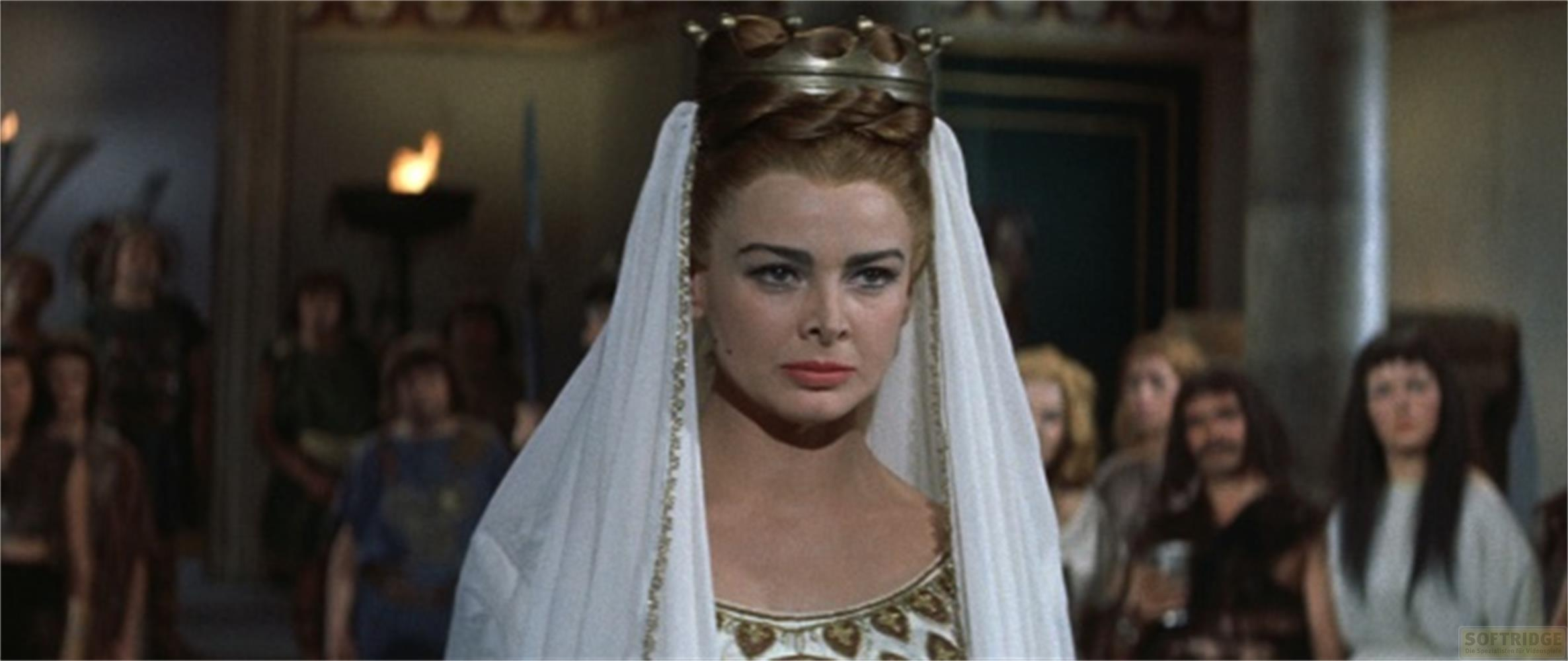 Regina con corona e velo, circondata da persone in abiti scuri.