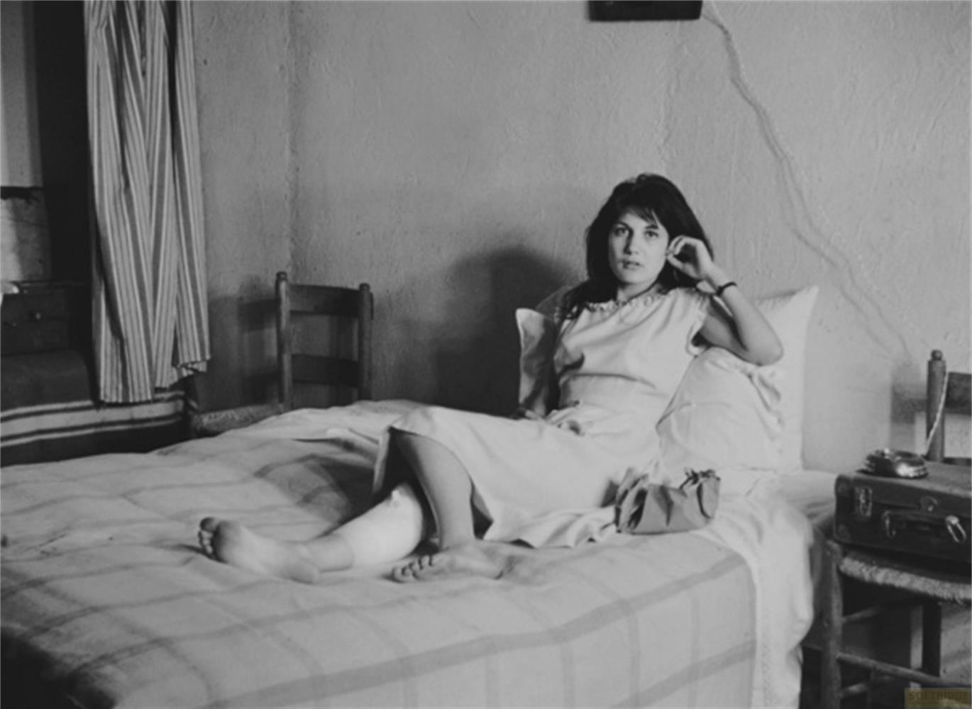 Una donna con una gamba fasciata è seduta su un letto.