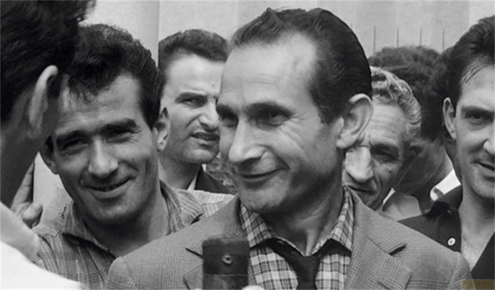 Diversi uomini vicini, uno sorride alla telecamera.