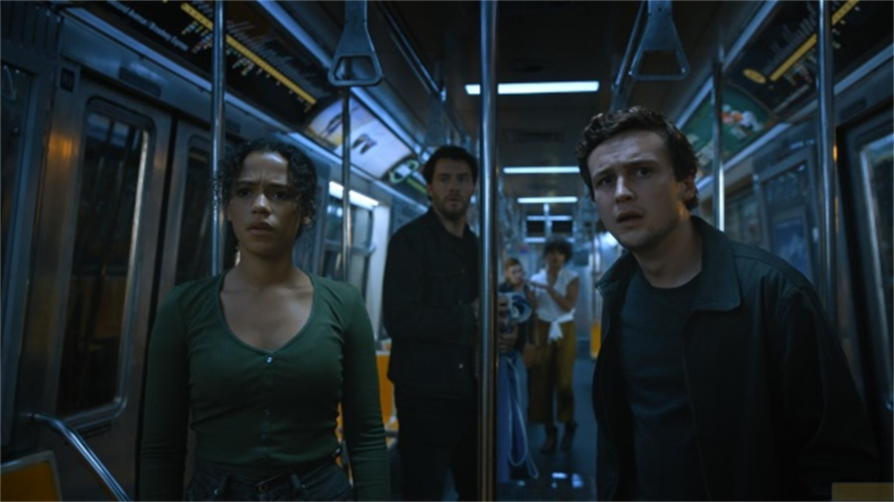 Quattro persone si guardano intorno con paura all'interno di un vagone della metropolitana poco illuminato. Una donna davanti guarda a sinistra.