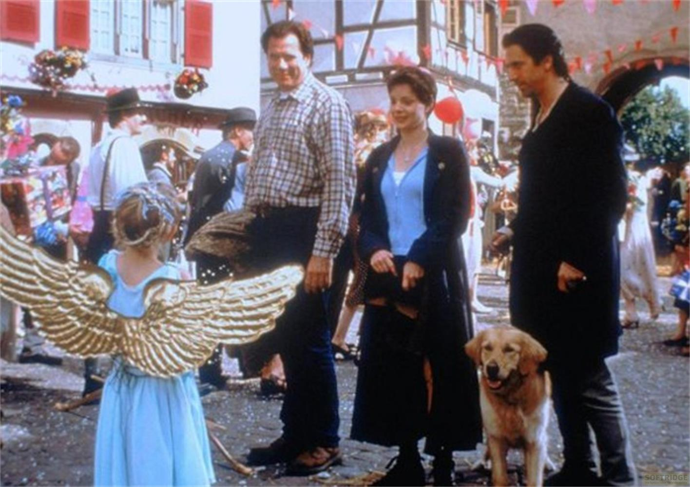 Una bambina con ali d'angelo dorate sta con un uomo e un cane.