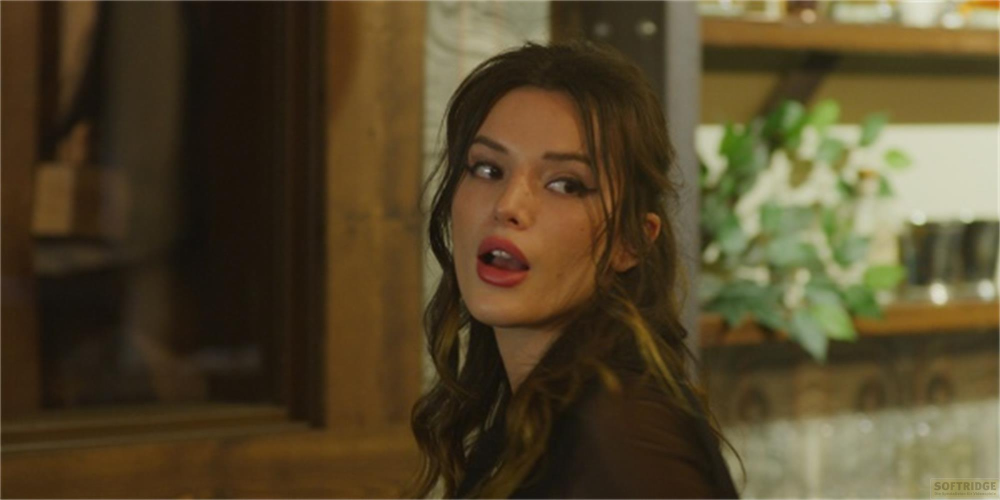 Una donna con i capelli castani e il rossetto rosso guarda di lato.