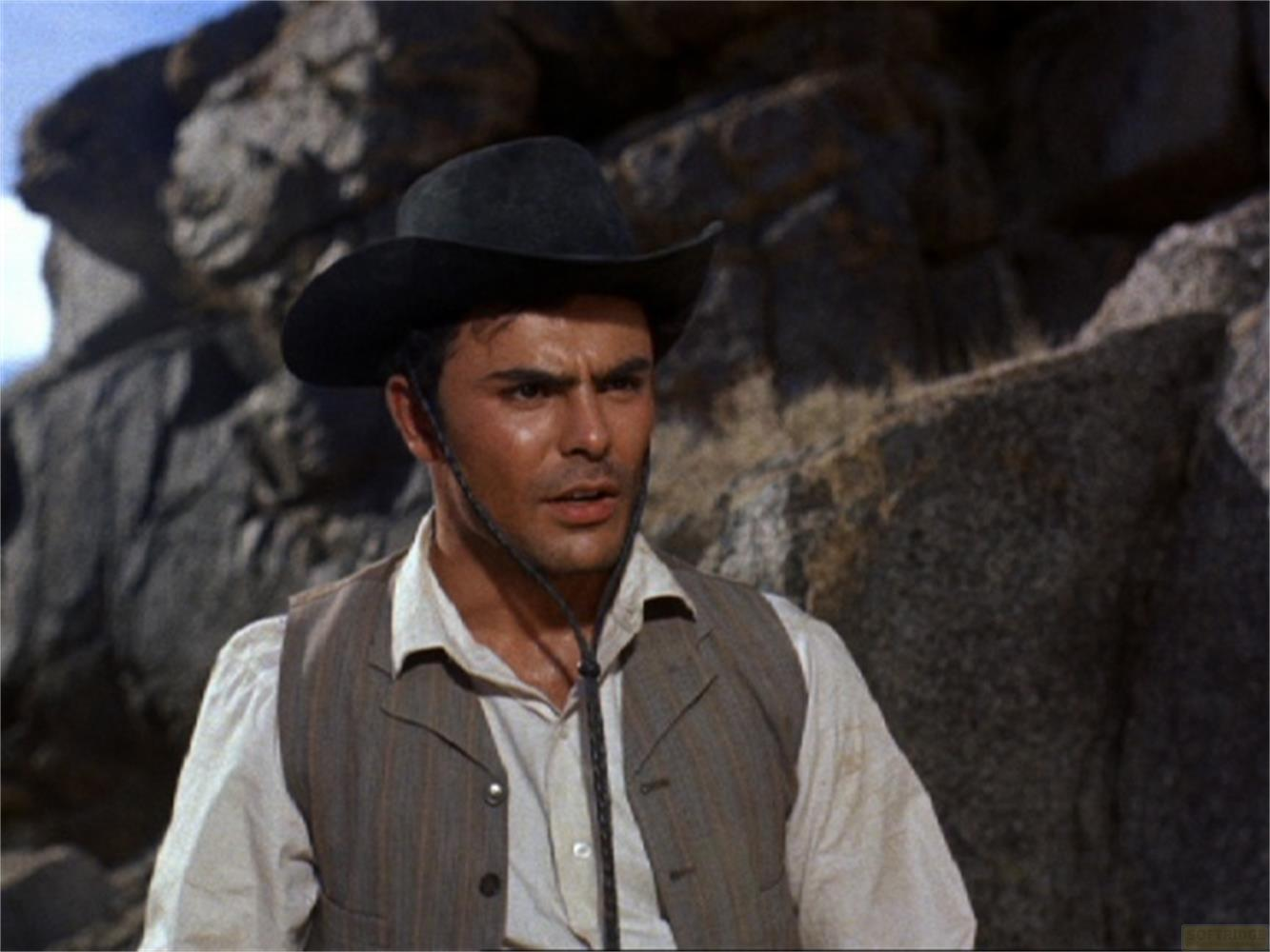 Un uomo con cappello e gilet da cowboy davanti alle rocce.
