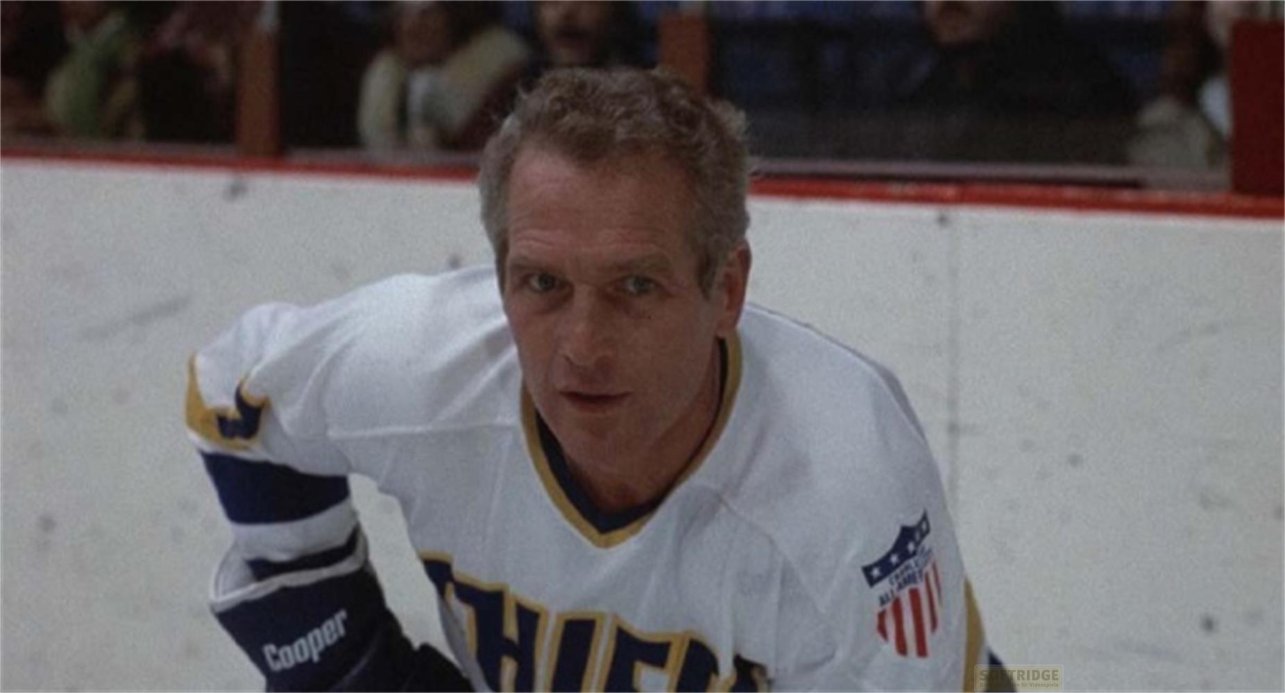 Un homme en maillot de hockey blanc avec des touches bleues et jaunes regarde devant lui.