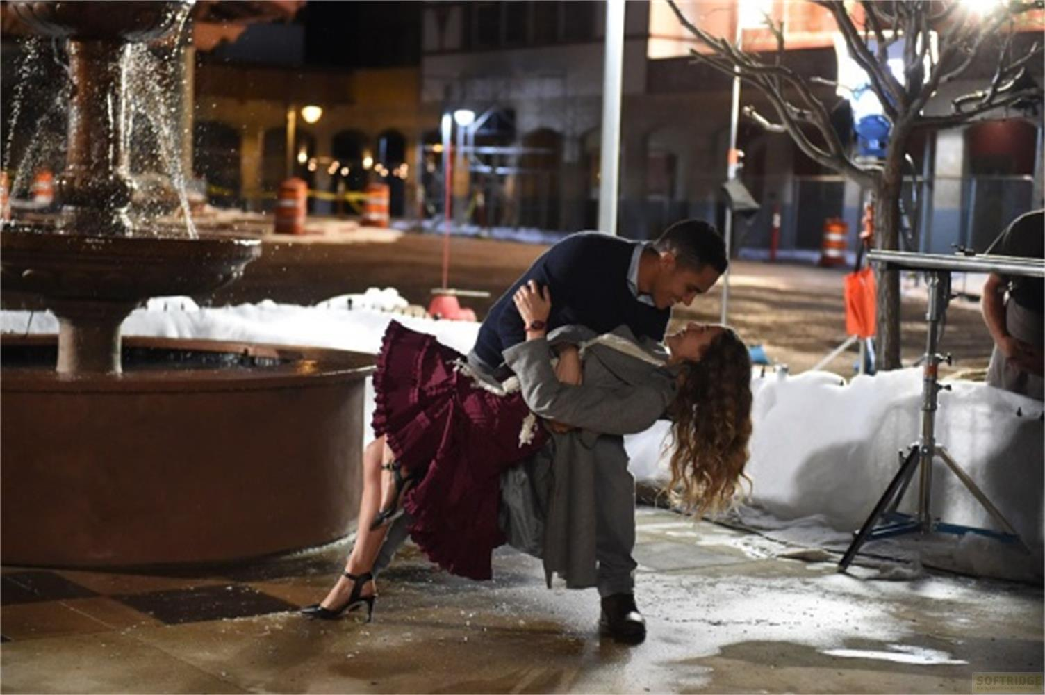 Uomo fa un inchino alla donna in un ballo romantico davanti a fontana e neve finta.