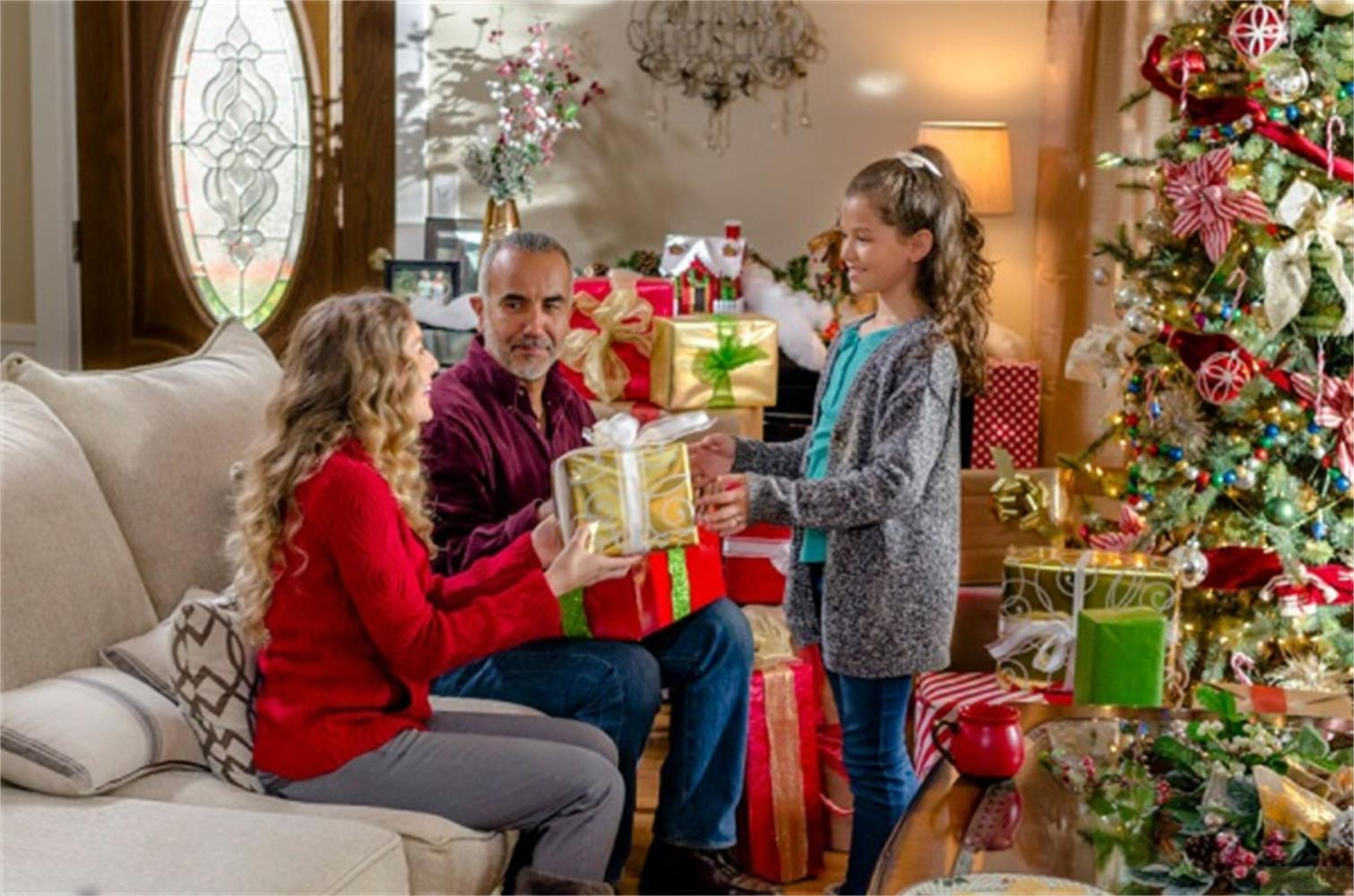 Famiglia scambia regali davanti all'albero di Natale.