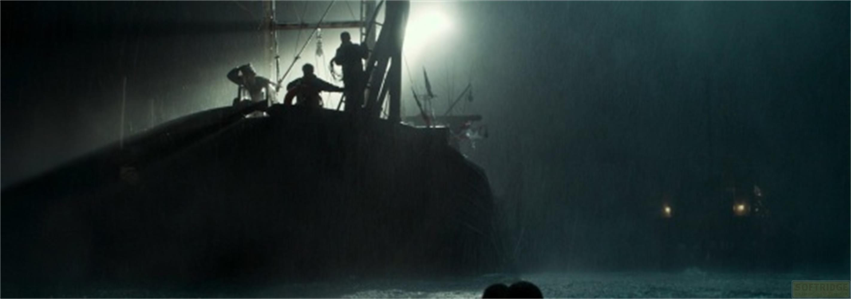Silhouette di persone su una nave sotto la pioggia di notte, con luci sullo sfondo.