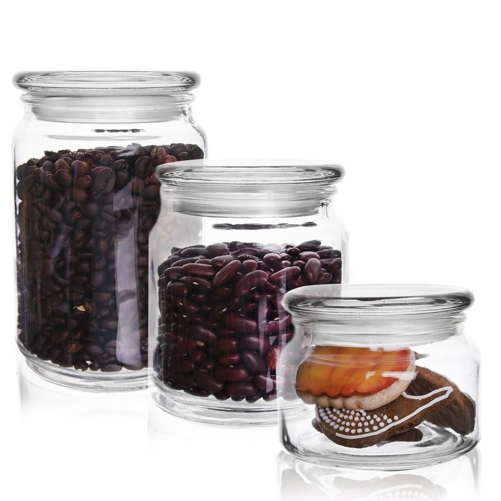 Tres frascos de vidrio con tapa: uno con granos de café, uno con frijoles rojos, uno con galletas.
