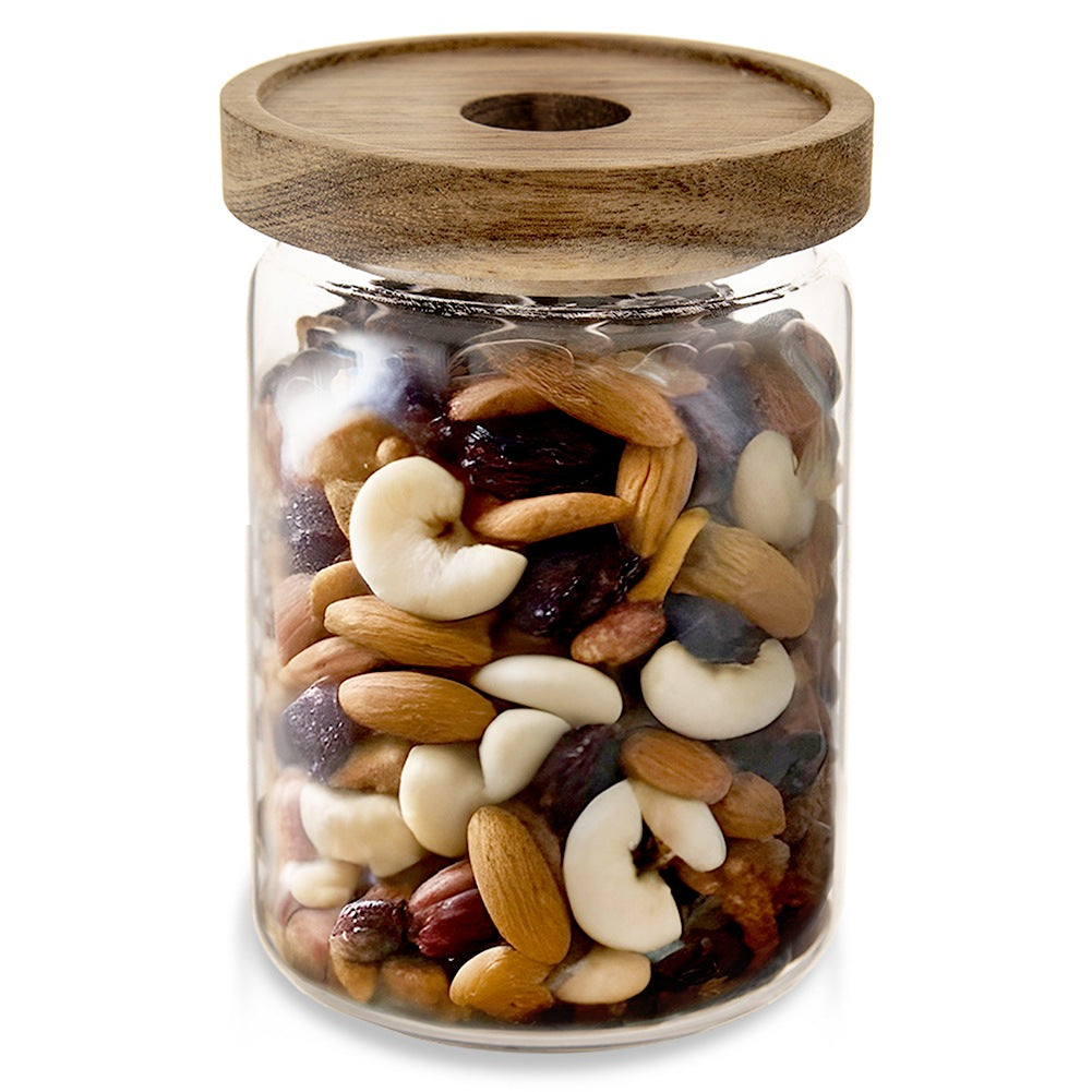 Frasco de vidrio lleno de frutos secos mixtos y pasas, con tapa de madera.
