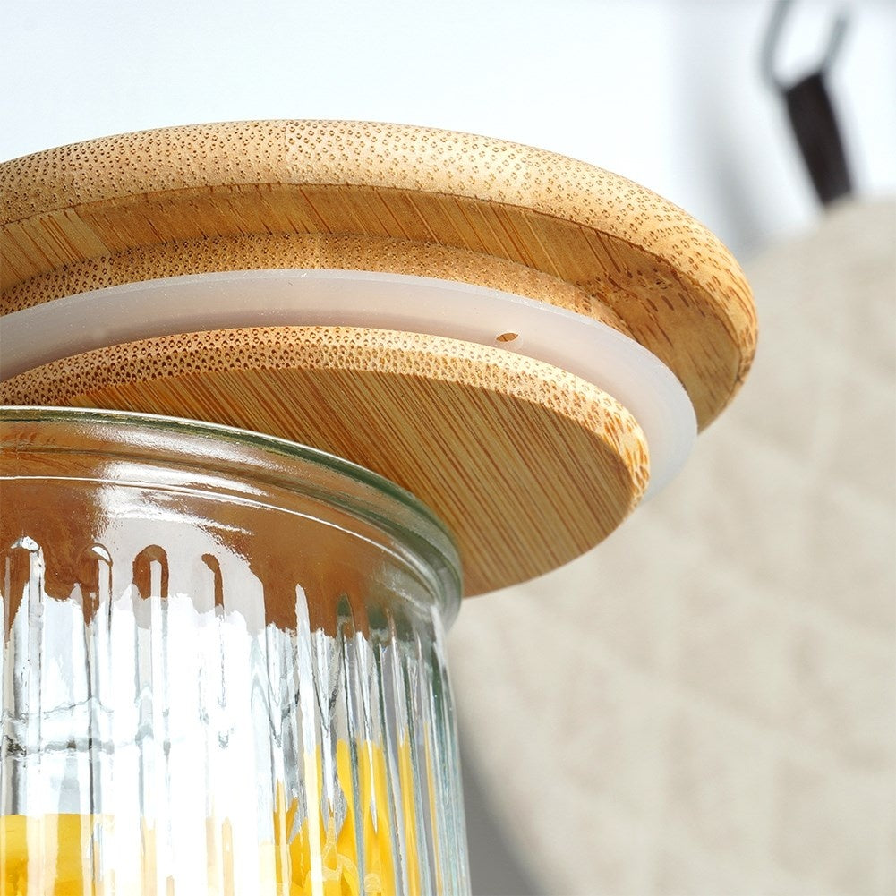 Coperchio in legno con guarnizione su un contenitore di vetro scanalato con contenuto giallo.