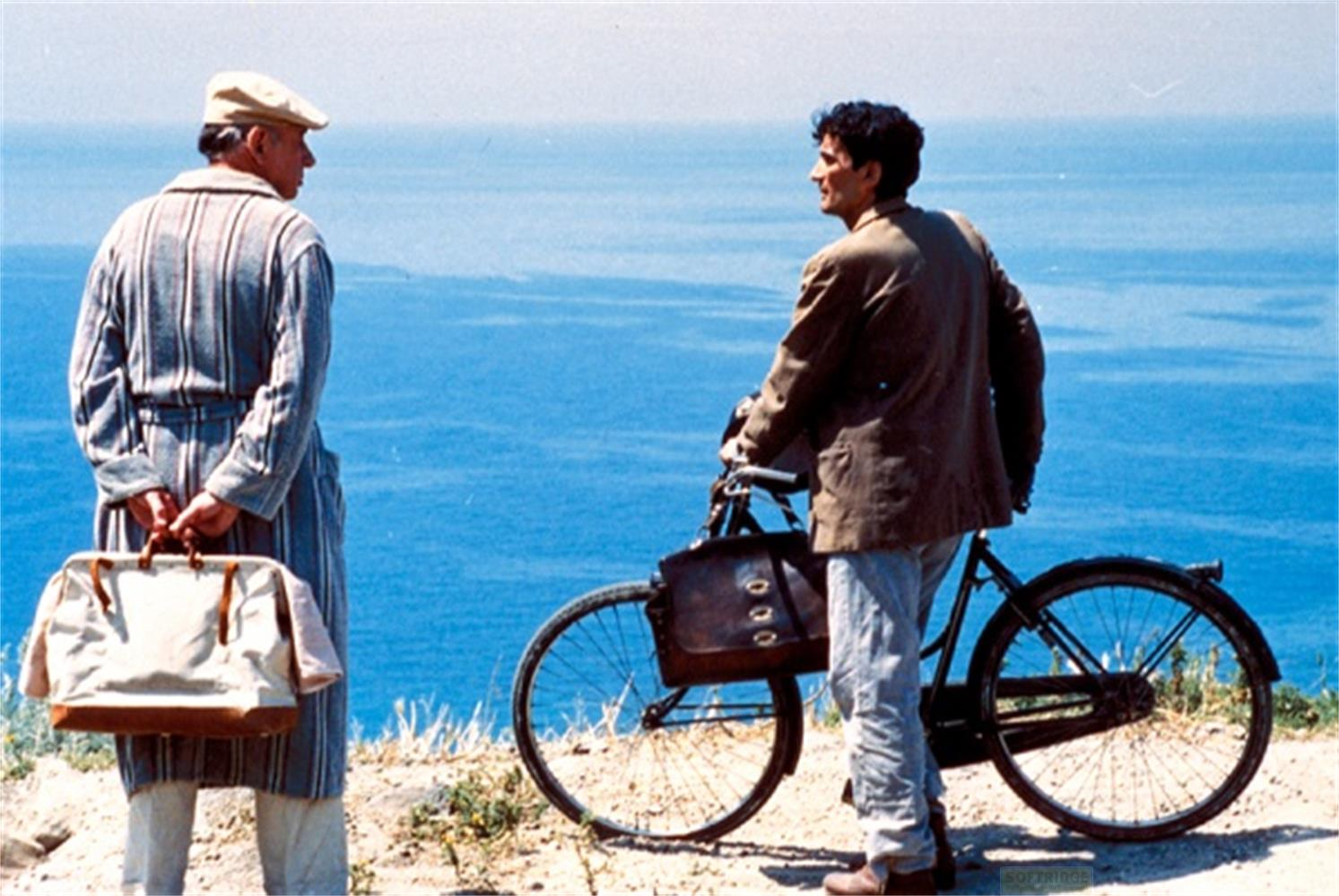 Deux hommes au bord de la mer. L'un tient un sac, l'autre un vélo.
