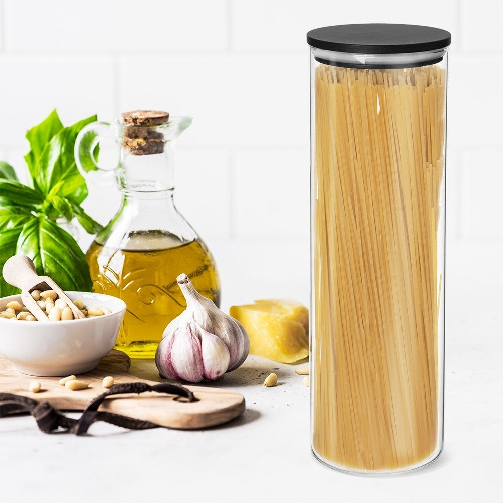 Espaguetis en frasco de vidrio junto a aceite de oliva, ajo, piñones y albahaca.
