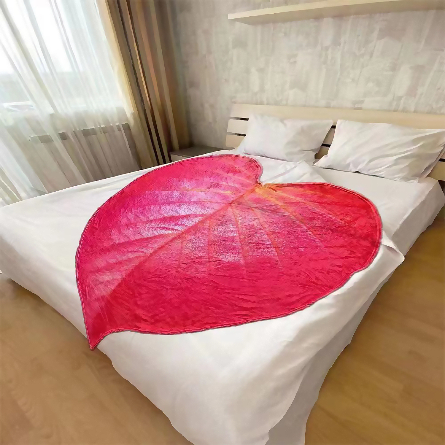 Ein Bett mit weißen Laken und Kissen, bedeckt mit einer roten Herzdecke.