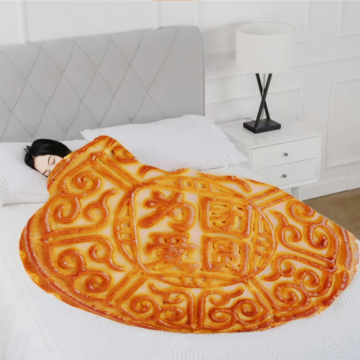 Una persona dorme sotto una coperta a motivo di torta lunare.