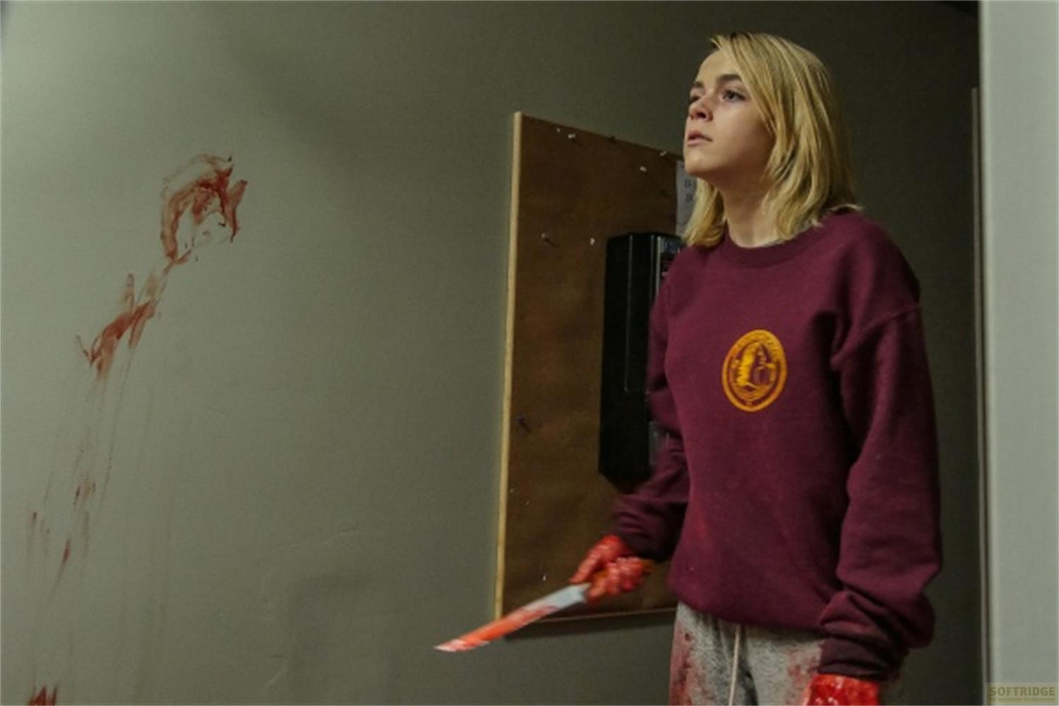 Fille aux mains ensanglantées tenant un couteau; mur ensanglanté.