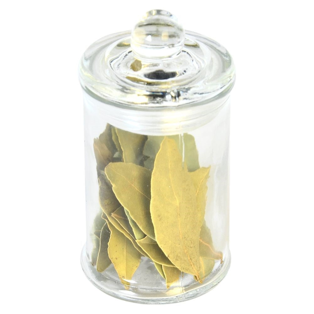 Un frasco de vidrio con hojas de laurel secas y tapa.