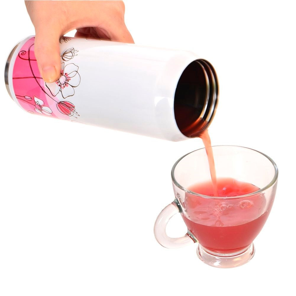 Una mano vierte jugo rosado de un recipiente blanco en una taza de vidrio.