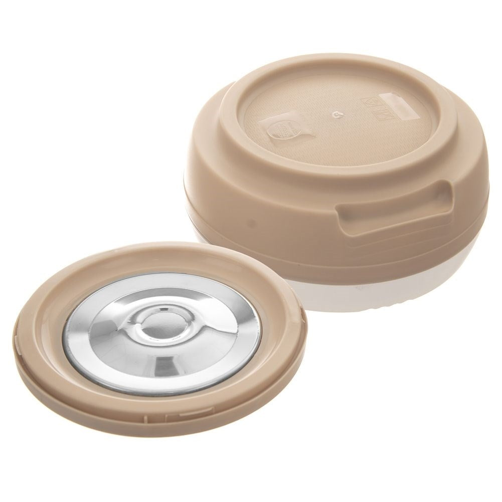 Una tapa de contenedor beige con inserción plateada yace junto al contenedor.