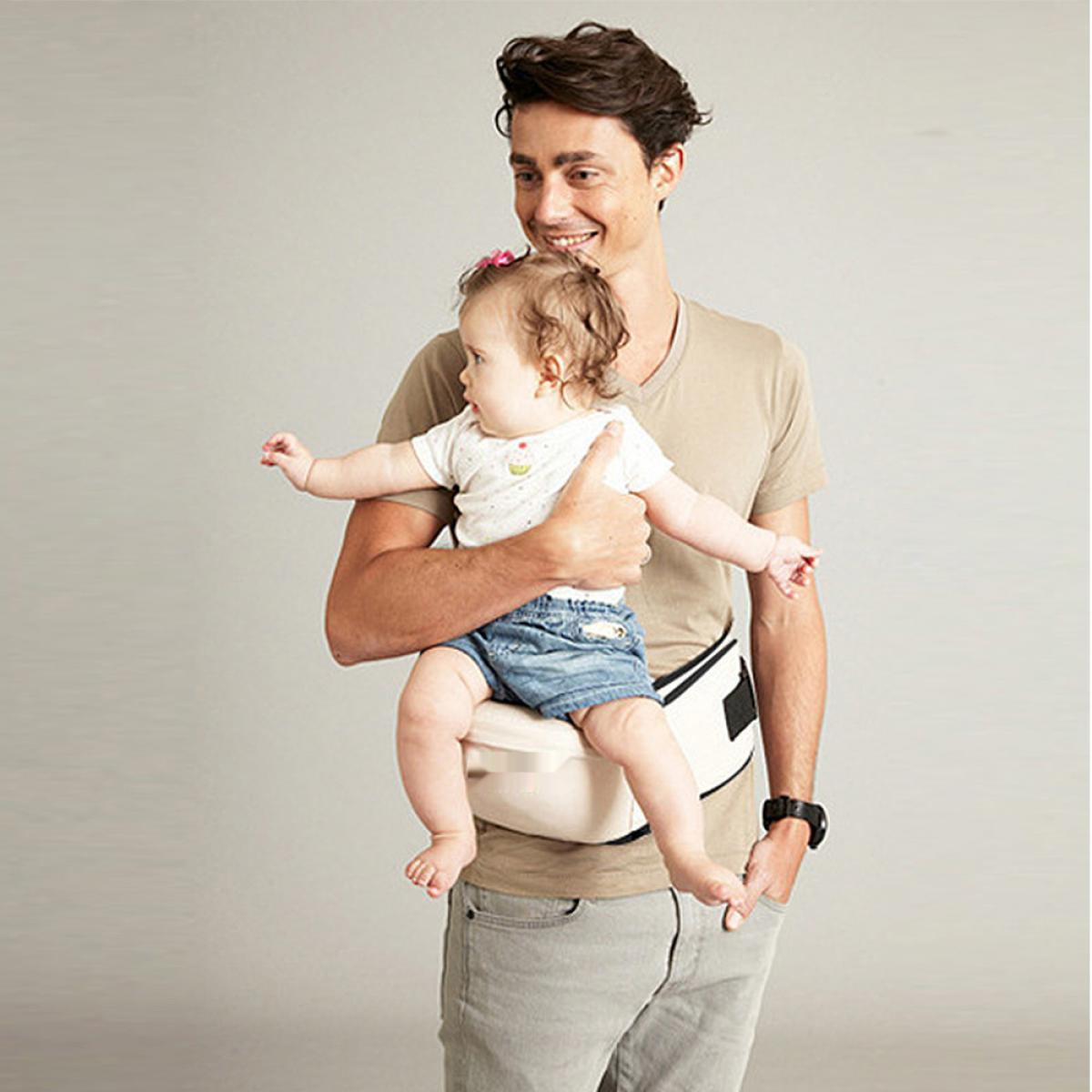 Mann mit Baby-Tragehilfe, Baby im Arm, lächelnd.