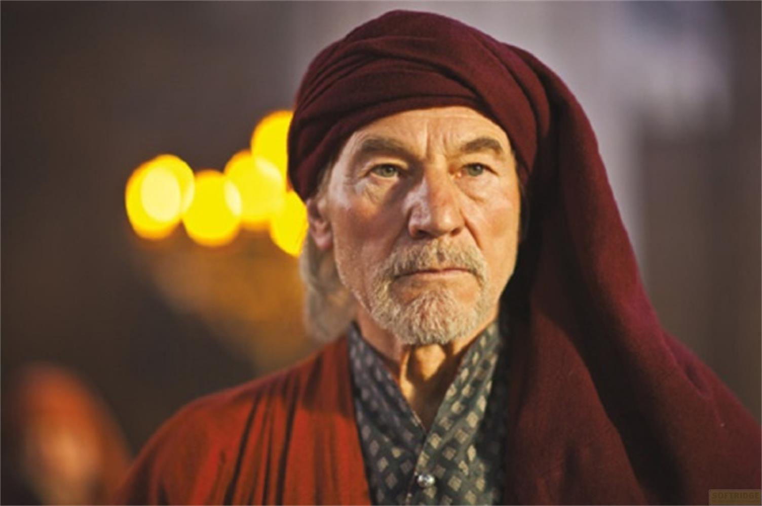 Un uomo anziano con barba grigia indossa un turbante e una veste rossa.