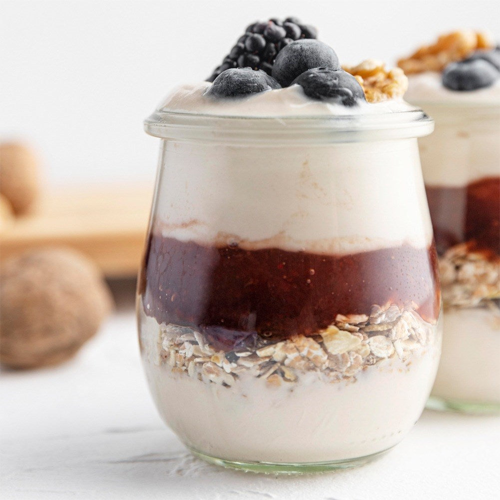 Parfait de yogur en vaso con bayas, mermelada y granola.