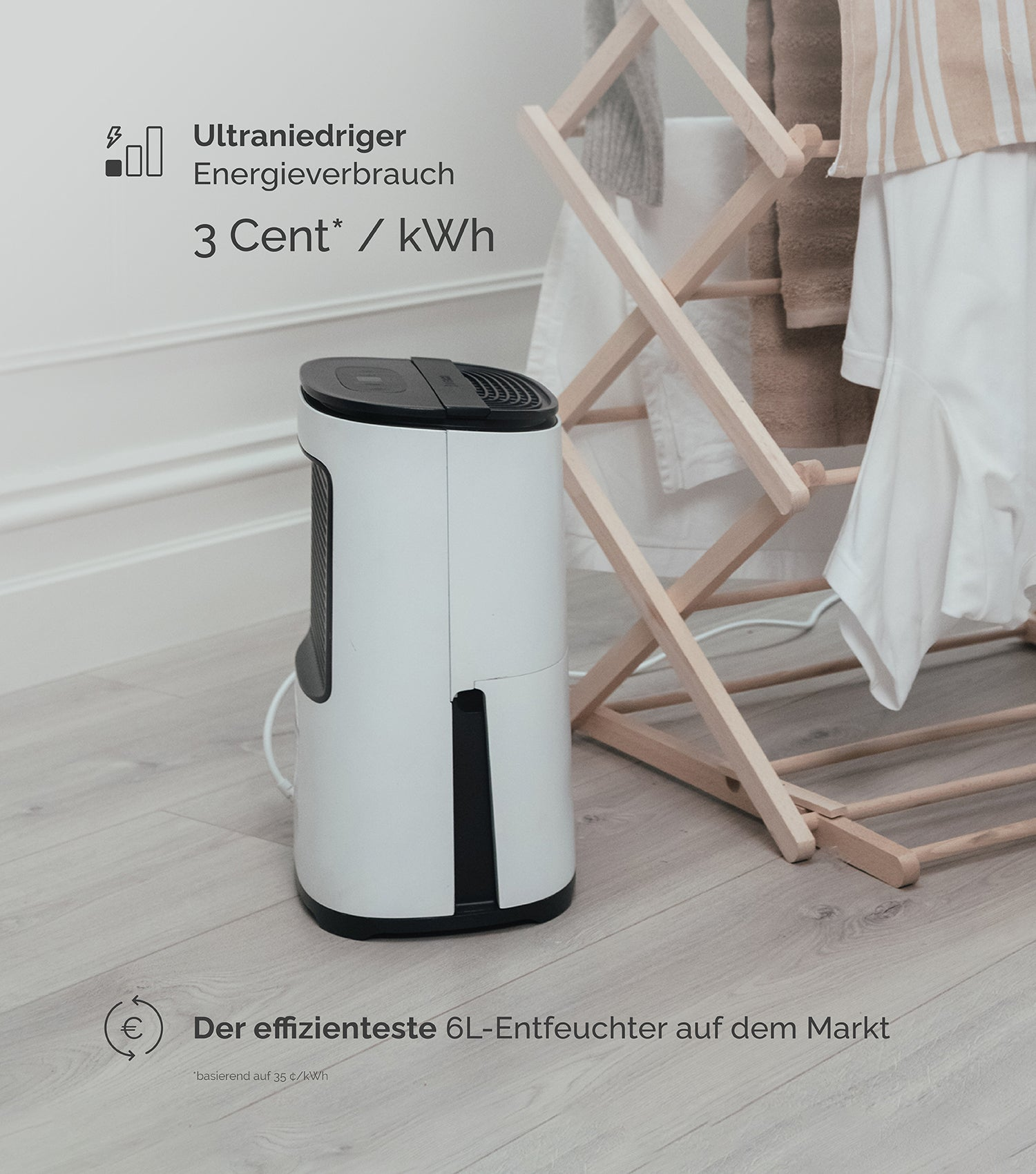 Ein weißer Luftentfeuchter steht neben einem Wäscheständer mit Kleidung.