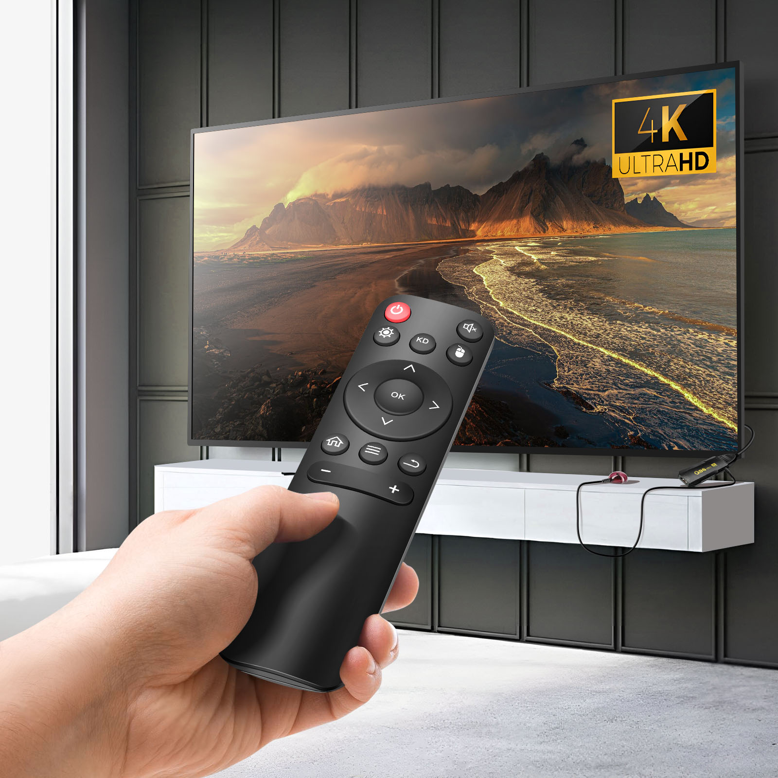 Mano con telecomando davanti TV 4K con paesaggio montano.