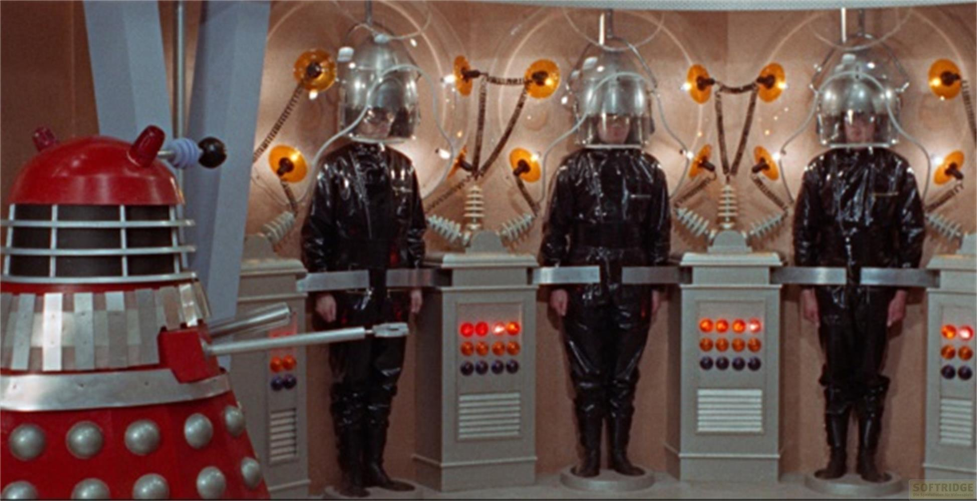Un Dalek è accanto a tre persone in abiti e caschi neri.