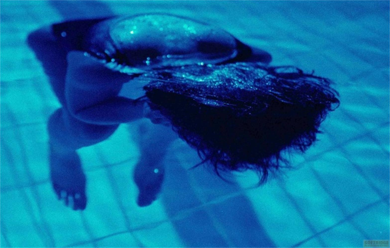 Persona sott'acqua, capelli coprono il viso, piedi visibili.