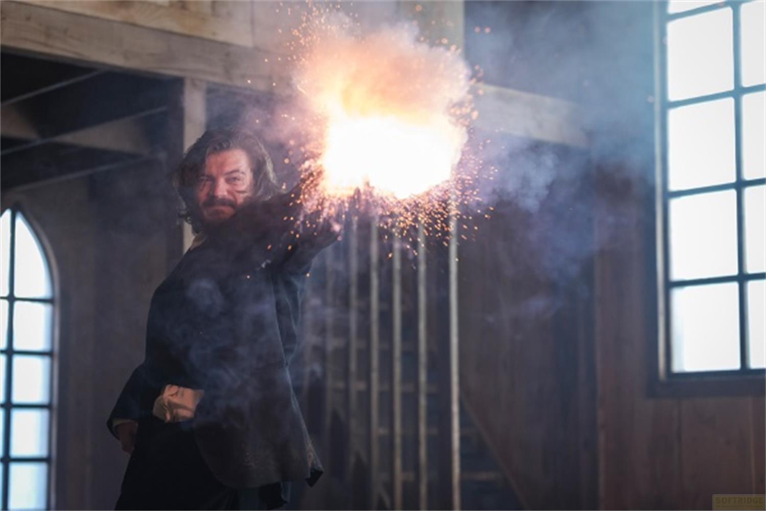 Un uomo spara con una pistola, fiamme e scintille eruttano.