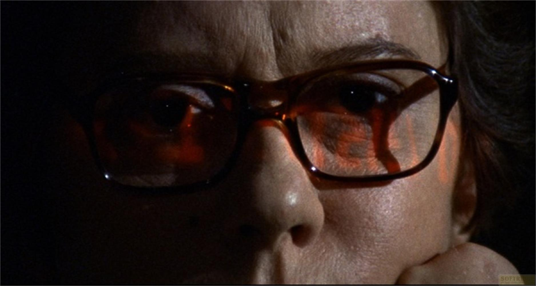 Gros plan d'un visage portant des lunettes avec des reflets rouges.