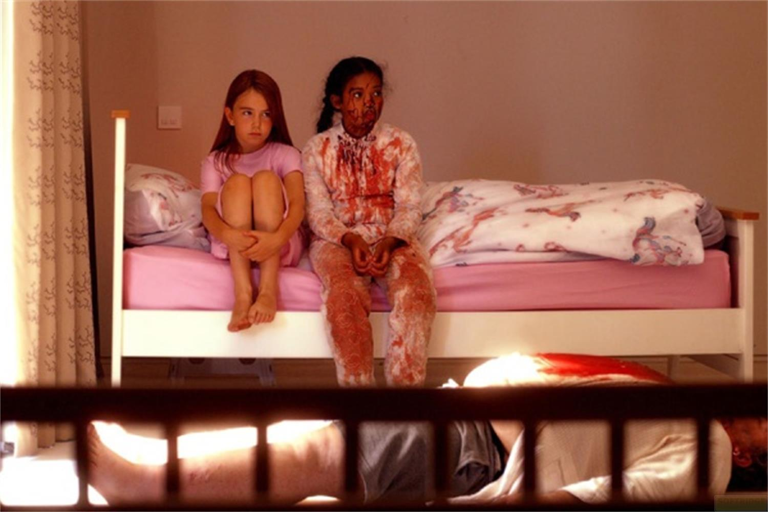 Due bambine sedute su un letto. Una è pulita, l'altra ha macchie rosse.