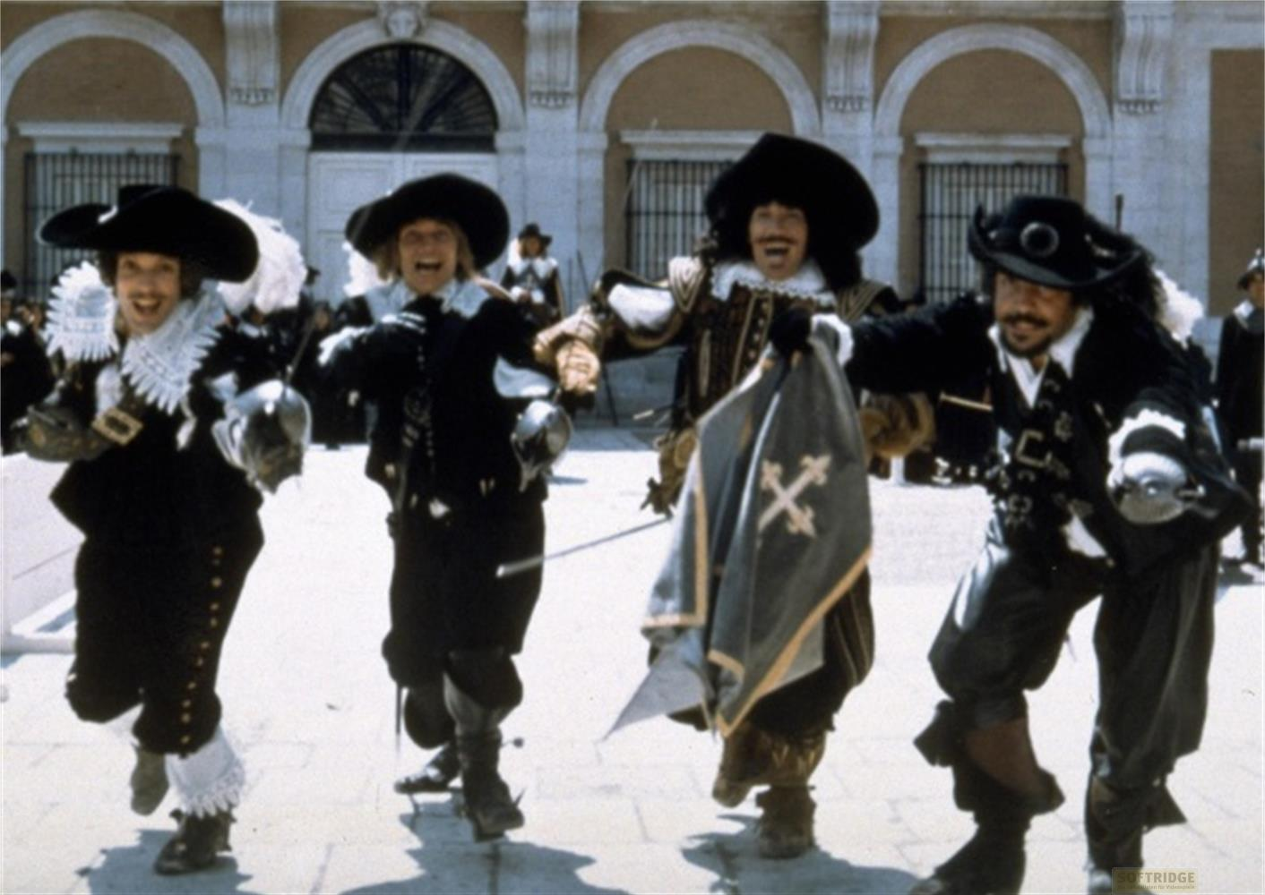 Quattro attori in costume da moschettiere, con cappelli e spade, corrono in una piazza.